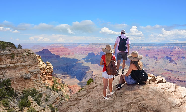 Three hikers stand on the edge of the Grand Canyon