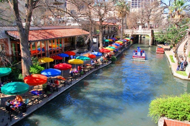 A boat floating down The San Antonio river near The Riverwalk.