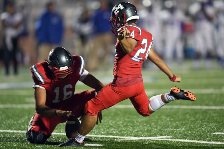 A football player sets up a kick for a quarterback at a Texas football game