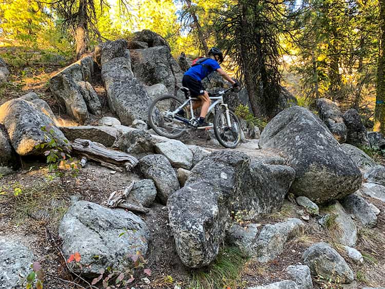A teen rides a mountain bike on a rocky trail