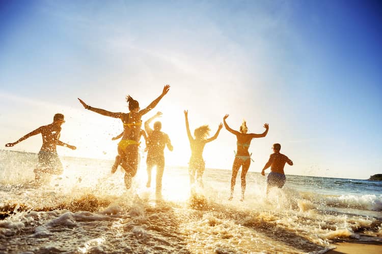 friends jump and run into the ocean water at a miami beach