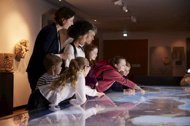 Pupils On School Field Trip To Museum Looking At Map