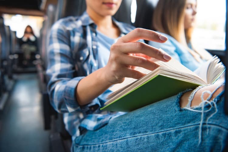 A person reading a book on a bus.