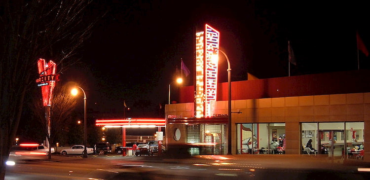 The Varsity's main sign lit up at night, with patrons enjoying food inside the windows